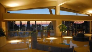A spacious indoor area with large windows offering a view of the sunset. - LABRANDA Rocca Nettuno Tropea (Tropea)