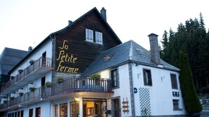 A two-story building with a sign reading "So Petite Ferme" and a balcony with potted plants. - The Originals Relais, Auberge de la Petite Ferme (Besse-et-Saint-Anastaise)