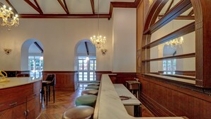 A restaurant with a long counter, wooden stools, and chandeliers. - Citrus Chambers Mahabaleshwar (Mahabaleshwar)
