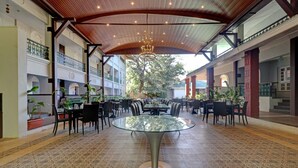 A spacious indoor area with a central glass-top table surrounded by chairs, a patterned floor, and a wooden ceiling. - Citrus Chambers Mahabaleshwar (Mahabaleshwar)