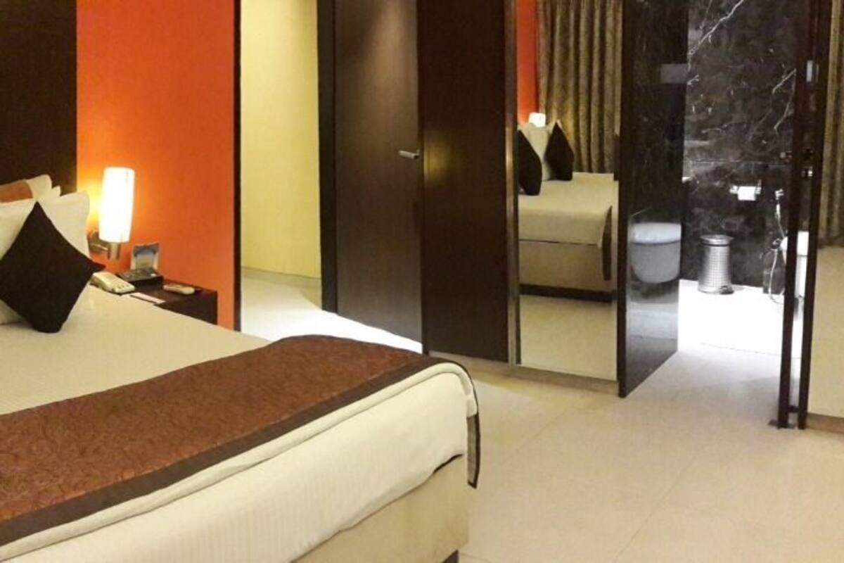 A hotel room with a bed, bedside lamps, a nightstand, and a mirror.