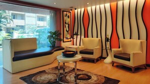 A modern living room with a sofa, two armchairs, a small table, and a decorative wall. - Citrus Hotel Lonavala (Mawal)