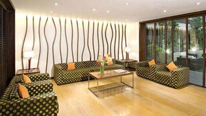 A modern living room with a sofa set, a coffee table, and a decorative wall panel. - Citrus Hotel Lonavala (Mawal)