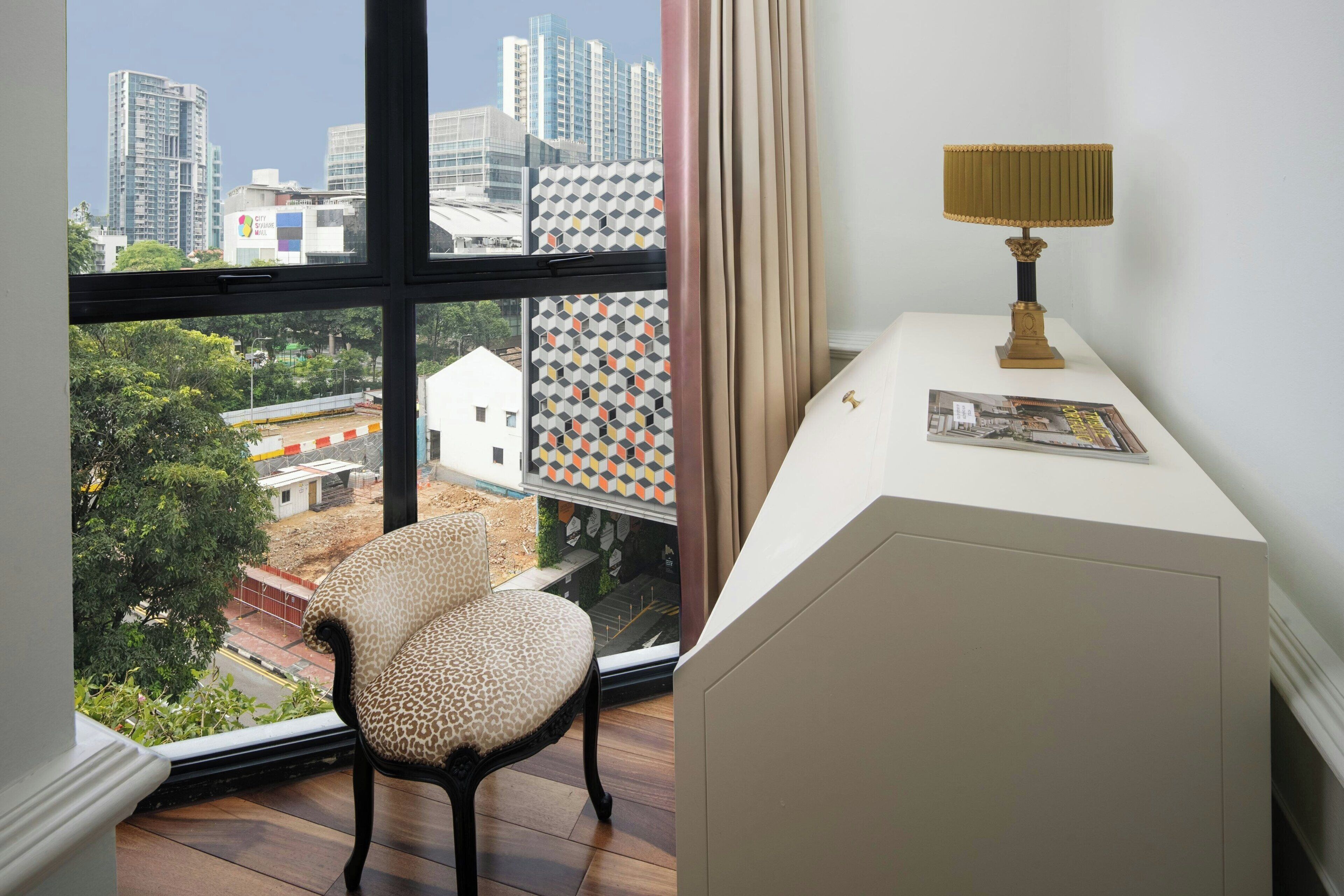 Une pièce avec vue sur la ville, une chaise, un bureau avec une lampe et un livre.