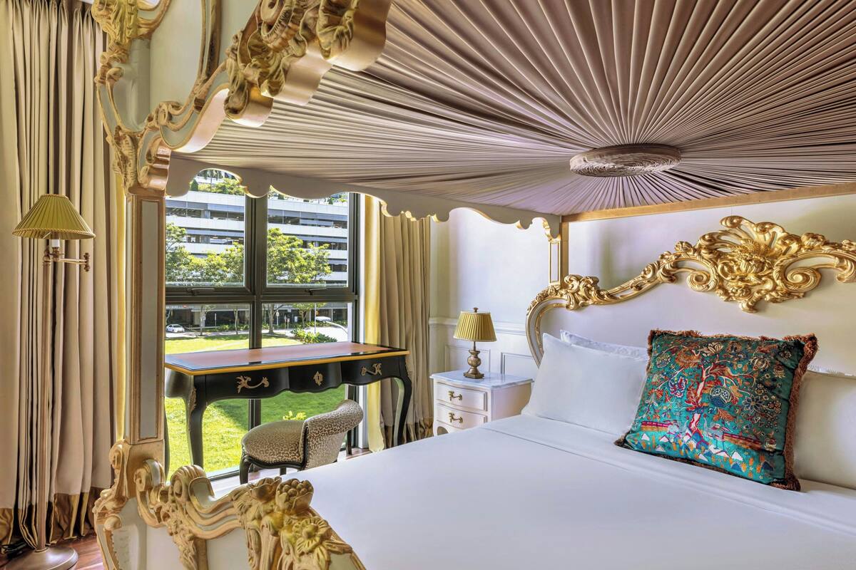 Camera d'albergo di lusso con un letto grande, soffitto decorato e vista su un edificio.