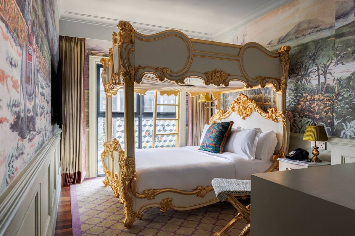 Una lussuosa camera da letto con un letto a baldacchino, un comodino e un'ampia finestra che si affaccia su un pavimento con motivo geometrico.