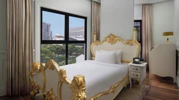 Ein Hotelzimmer mit einem großen Bett, einem Nachttisch, einer Lampe und Blick auf die Skyline durch das Fenster.
