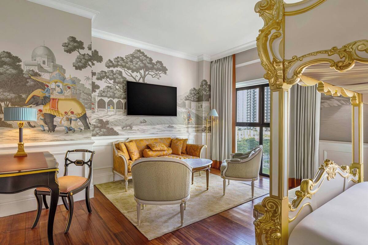 Una camera d'hotel di lusso con un letto grande, un divano, una TV e un affresco raffigurante degli elefanti.