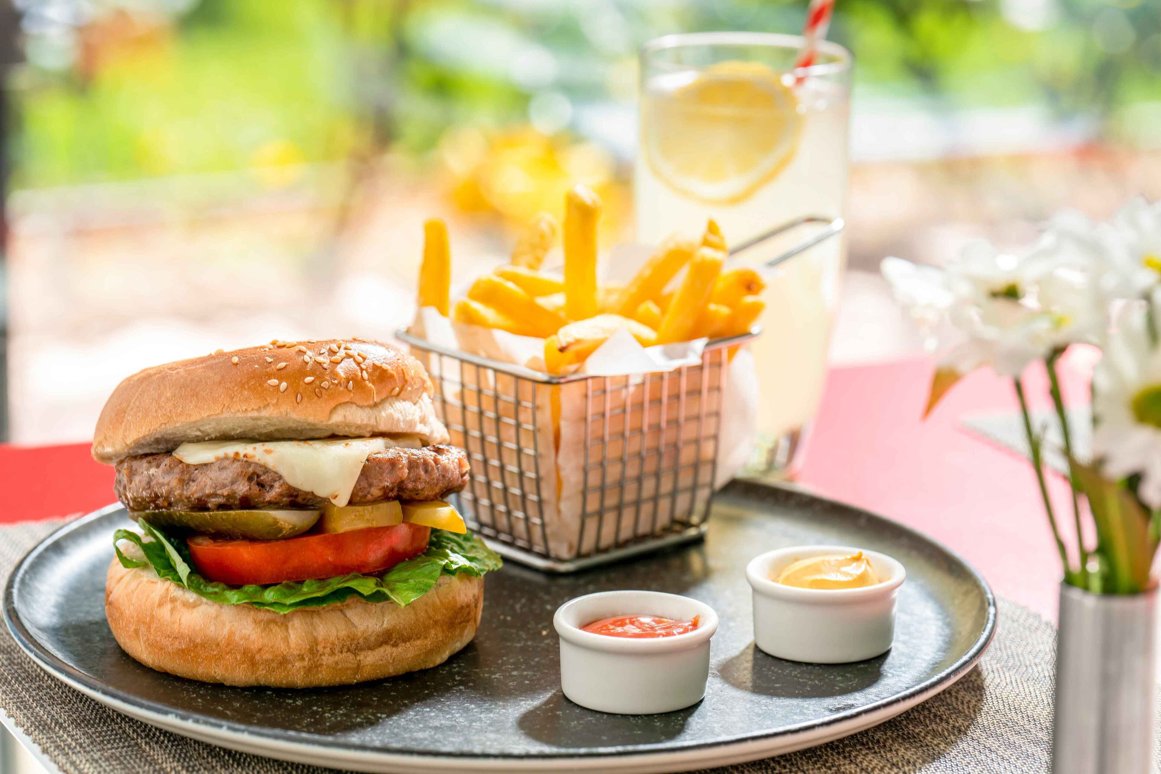 Un hamburger con patatine fritte e una bibita su un piatto.