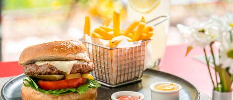 Un hamburger con patatine fritte e una bibita su un piatto.
