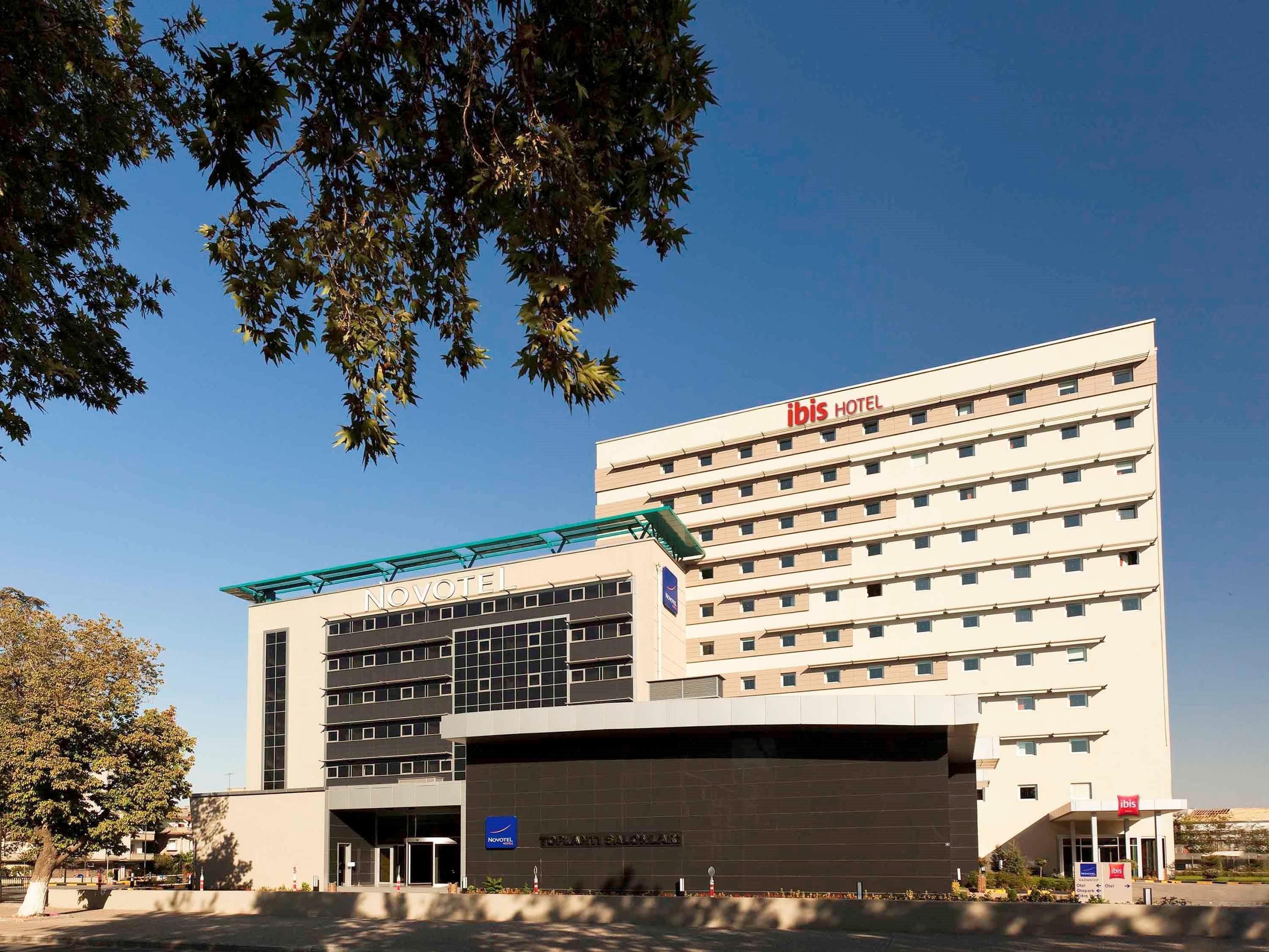 A Novotel hotel with a modern design, featuring a prominent 'Novotel' sign on the facade and an 'ibis' logo on the upper right.