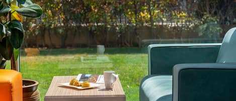 A modern outdoor seating area with a table, chairs, and a view of a garden.