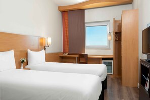 Habitación de hotel con dos camas, un escritorio, un televisor, un armario y una ventana.