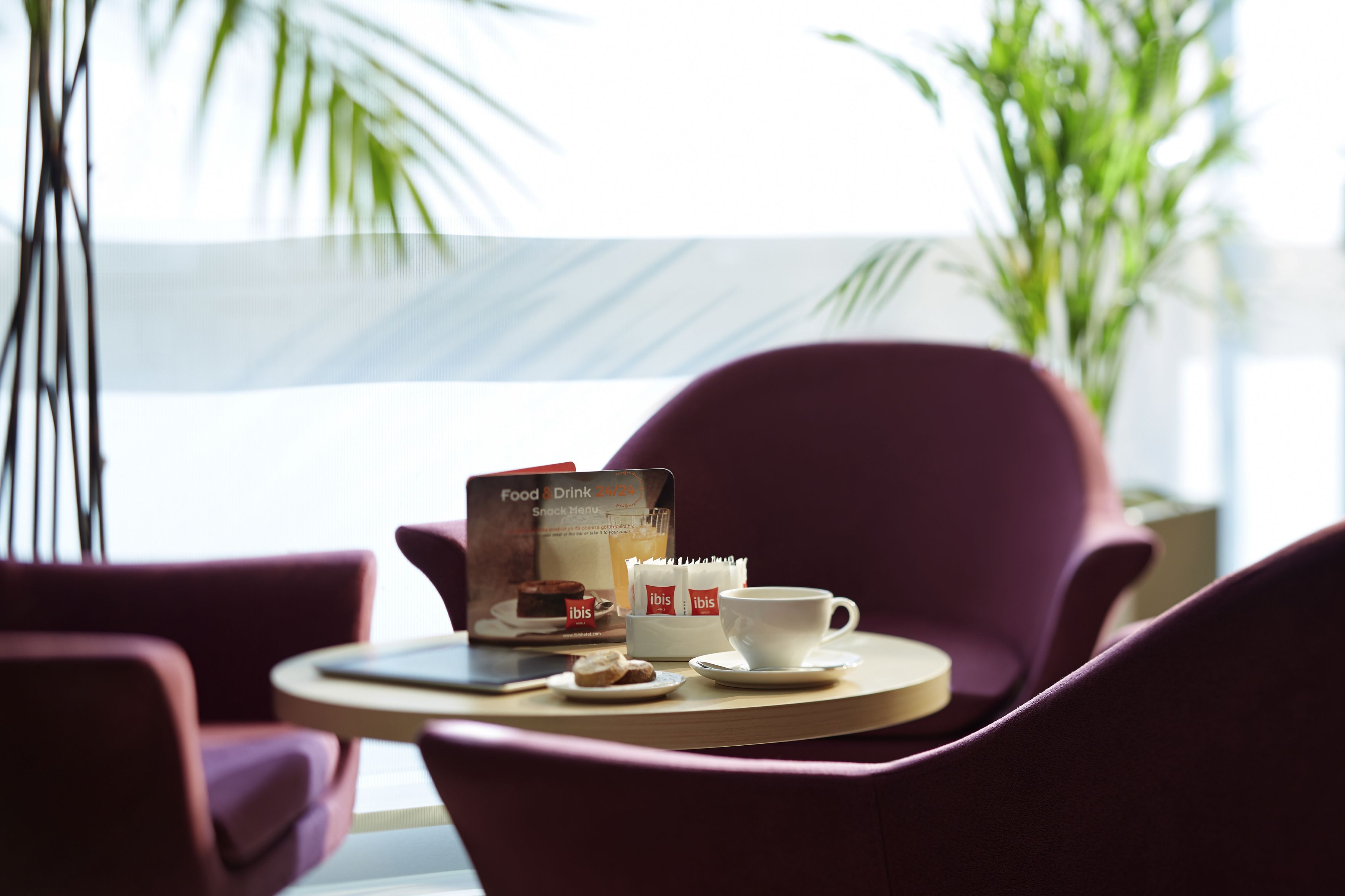 A dining area with a table set for two, featuring a menu, a cup, and a small plate with food.