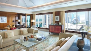 A spacious living room with a large sofa, a coffee table, and a view of the cityscape through large windows.