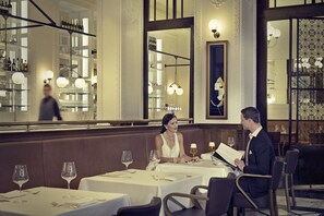 A restaurant with tables set for dining, a bar area with bottles, and a large mirror reflecting the interior.