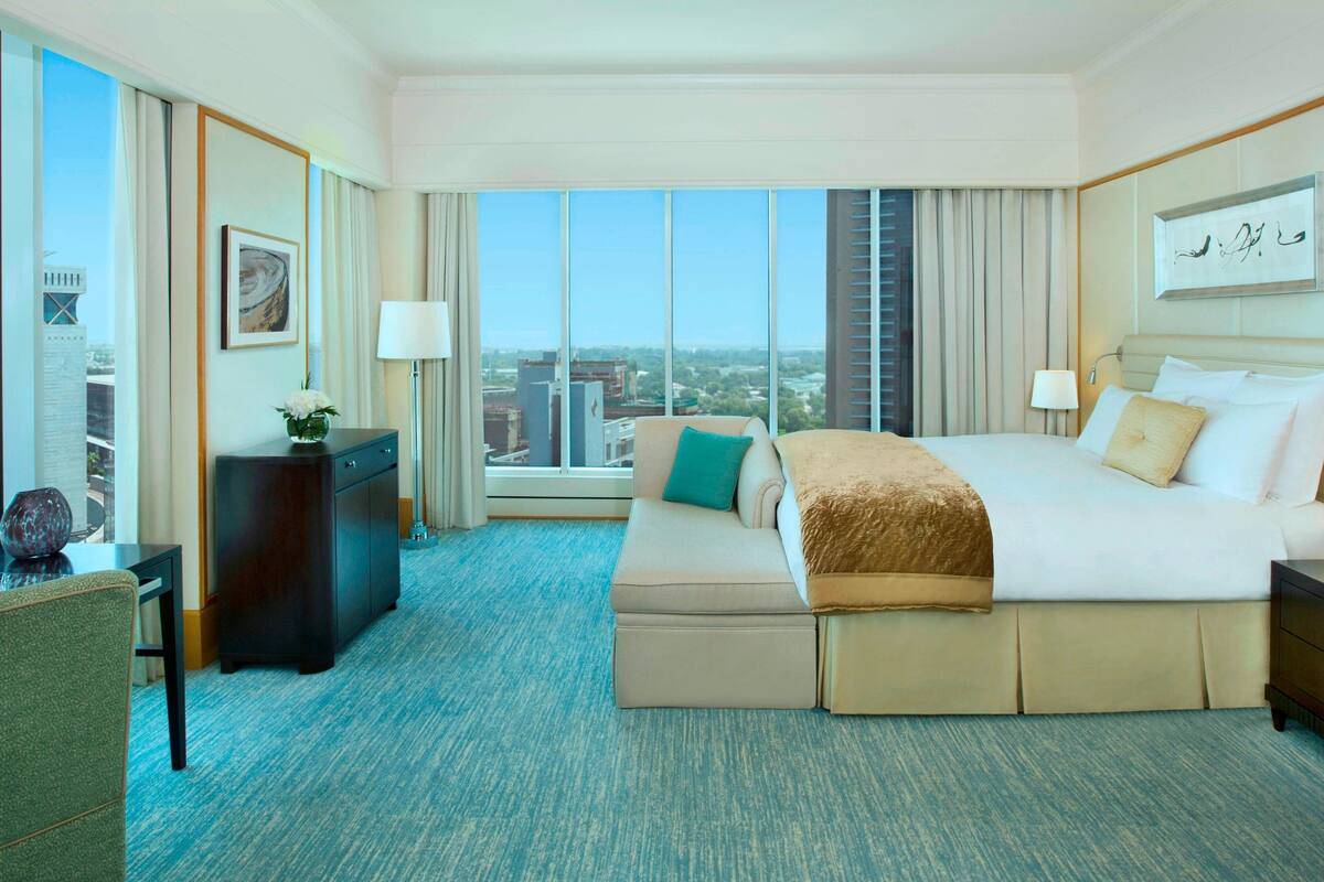 Quarto de hotel com uma cama grande, uma escrivaninha, uma cadeira e vista para a cidade.
