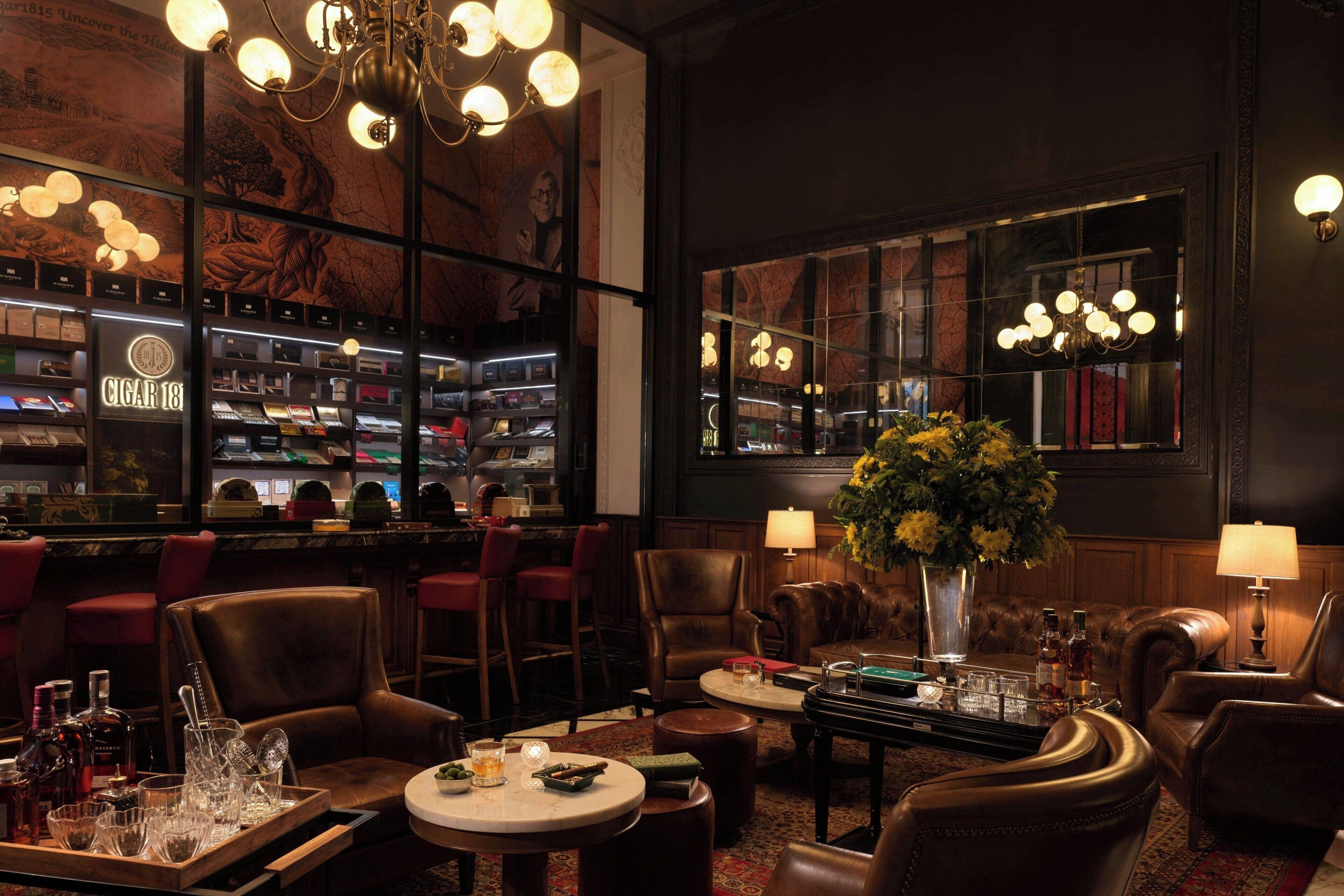 Un espace bar avec des fauteuils en cuir, un comptoir et une grande fenêtre.
