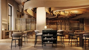 A modern interior with a central bar area, seating, and wine racks.
