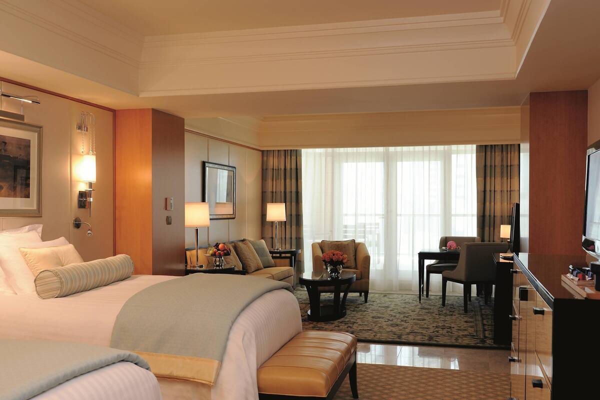 Quarto de hotel com uma cama grande, uma escrivaninha, uma cadeira e uma televisão.