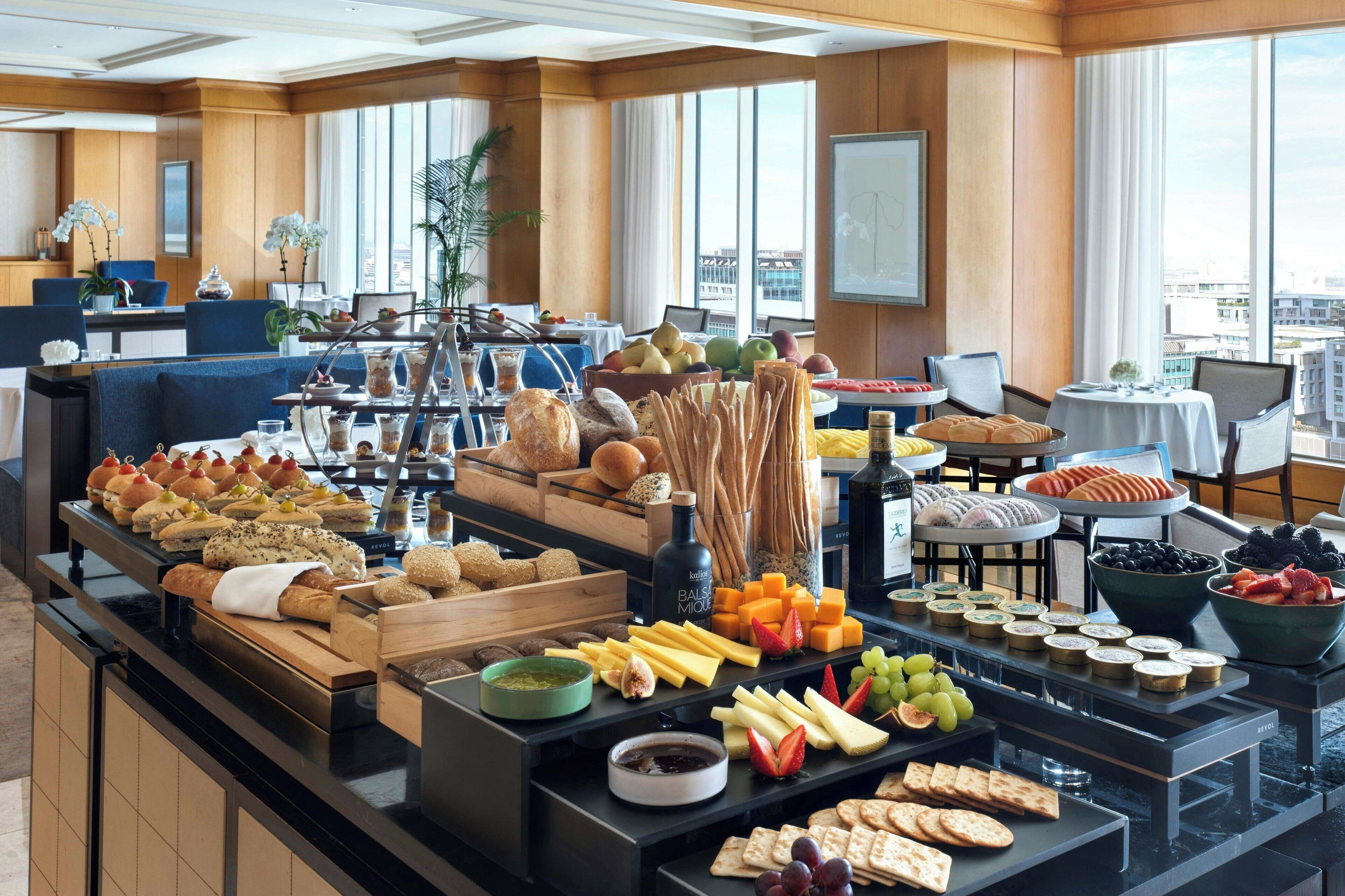 A buffet with various food items including breads, cheeses, fruits, and spreads.