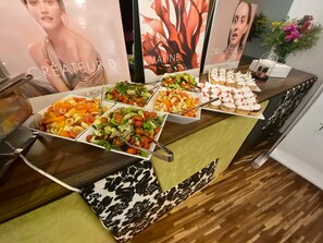 Ein reichhaltiges Buffet mit verschiedenen Speisen, darunter Salate, Früchte und Desserts.