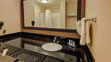 A bathroom with a black countertop, white sink, and a large mirror.