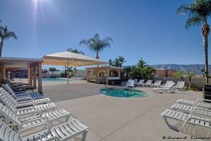 Ein Poolbereich mit Liegestühlen und Sonnenschirmen, ein kleiner Pool und Palmen.