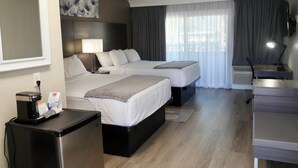 Ett hotellrum med två sängar, ett skrivbord, en stol, en kaffemaskin och en TV.