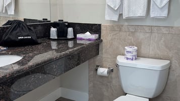 Un baño moderno con encimera de granito, inodoro blanco y toallero con varias toallas.