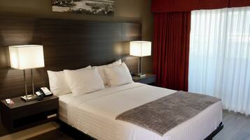 A hotel room with a large bed, two bedside tables with lamps, a painting on the wall, and a window with curtains.
