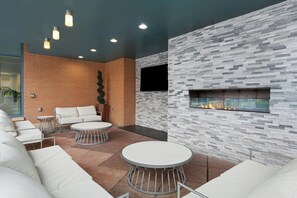 A modern lounge area with a brick wall, a fireplace, and a seating arrangement including a sofa and two round tables. - Club Wyndham National Harbor (Oxon Hill)