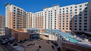 Un hotel de varios pisos con un patio central, piscina y un paseo cubierto.
