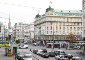 Uma rua urbana movimentada com edifícios históricos, um elétrico e diversas lojas.