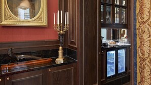 A luxurious interior with a marble countertop, a candelabra, a framed portrait, and a view through a glass cabinet. - Living Hotel an der Oper (Vienna)