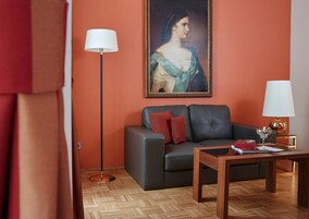 Sala de estar com sofá, duas luminárias de chão, um quadro e uma mesa de centro com um livro e um copo.