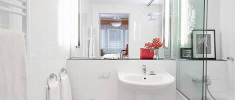 A modern bathroom with a glass shower enclosure, a white sink, and a small vanity area.