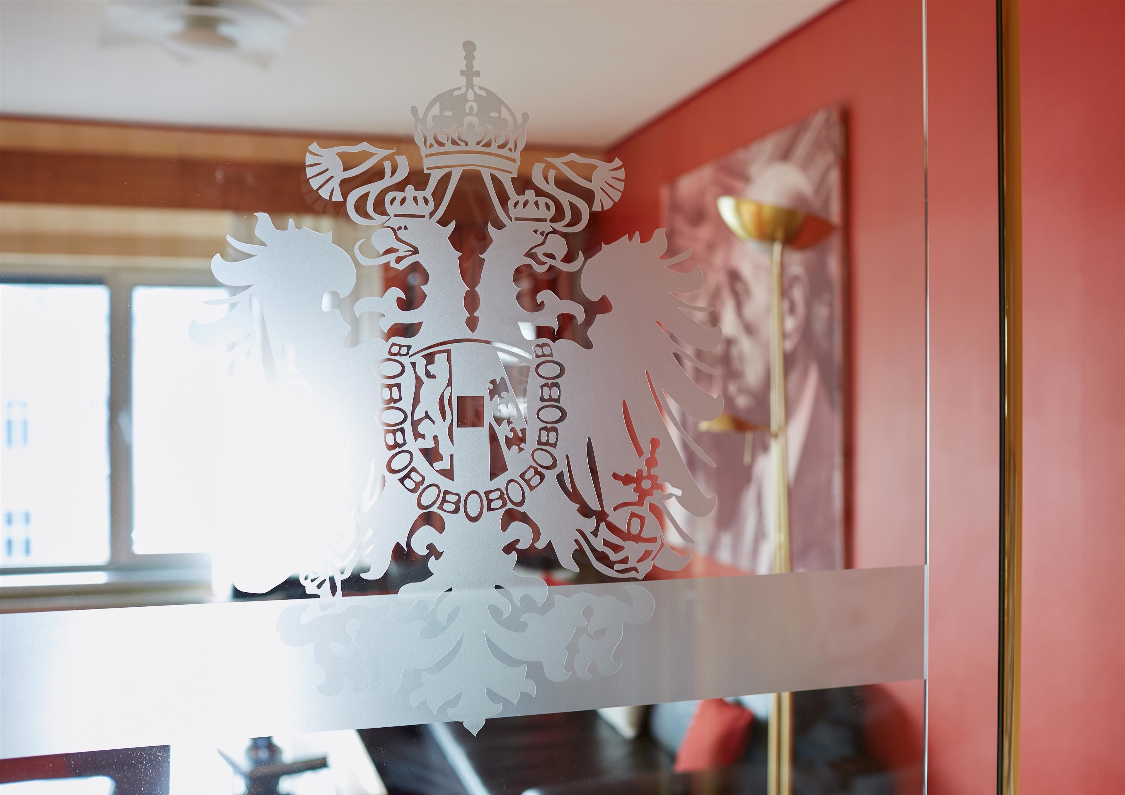 Una finestra amb un tall decoratiu, una corona i símbols heràldics.