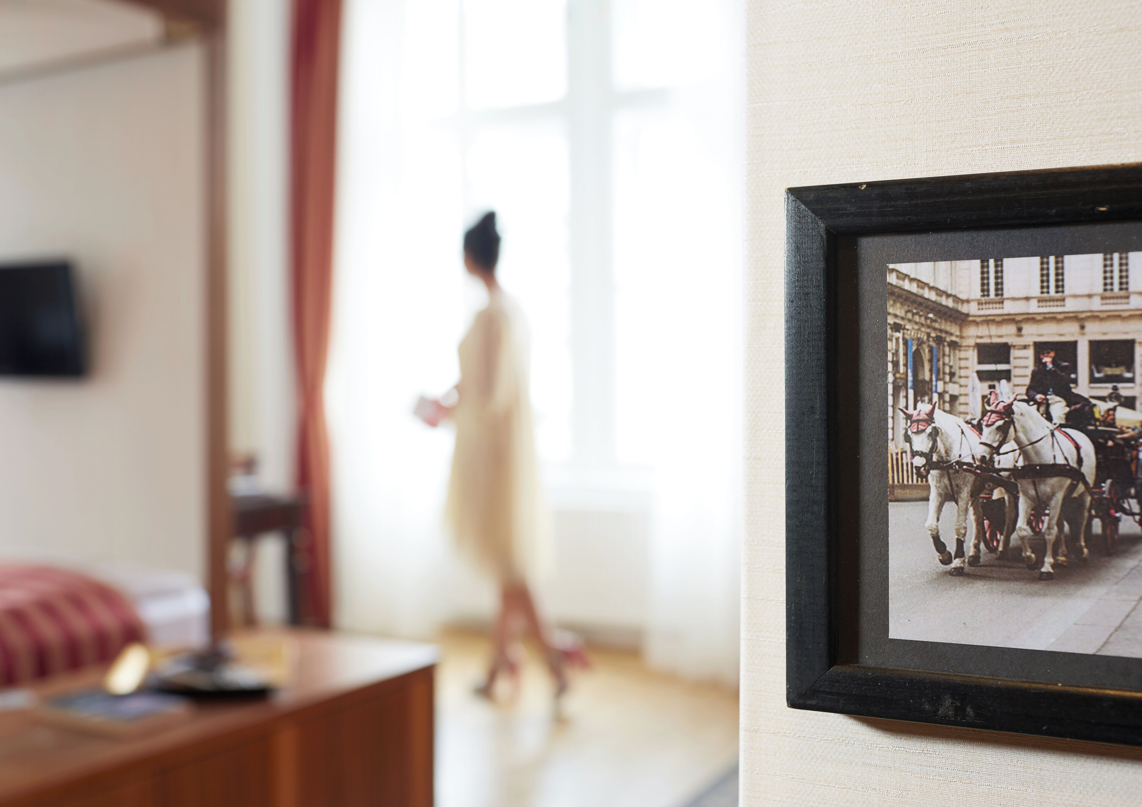 Una habitación con una fotografía histórica enmarcada en la pared, un escritorio de madera y una ventana con cortinas.