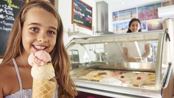 A person holding an ice cream cone in front of an ice cream display.