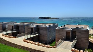 Un edificio moderno frente a la costa, con varias unidades, cada una con balcón y vistas al mar.