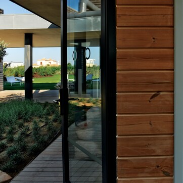 A modern room with a wooden wall, a bed, a small table, and a window.