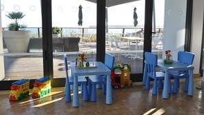 A children's play area with a table and chairs, toys, and a view of the sea.