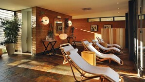 A spa area with sun loungers, wooden walls, and potted plants.