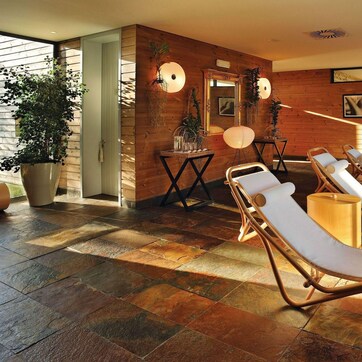 A spa area with sun loungers, wooden walls, and potted plants.