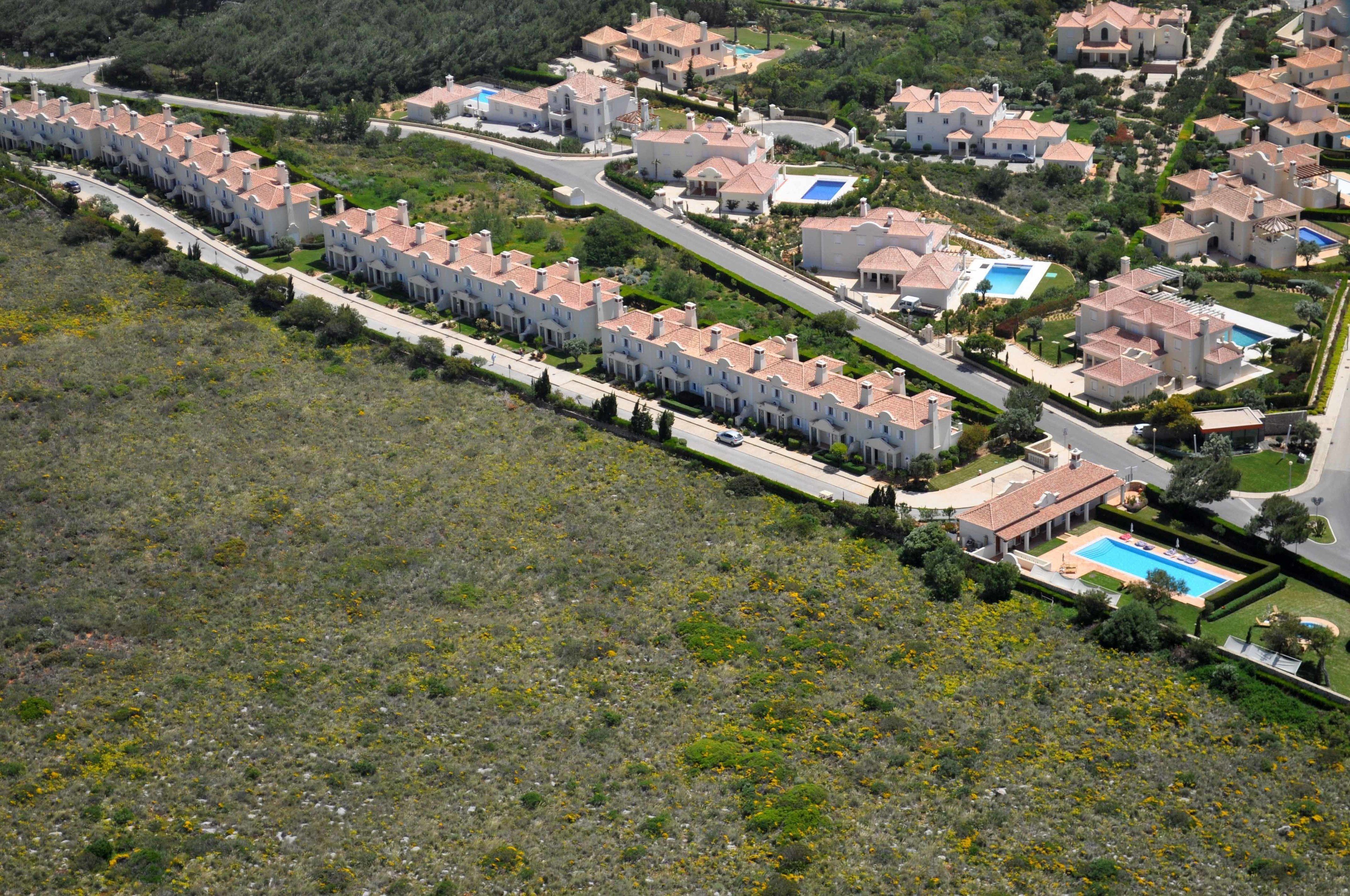 Vue aérienne d’un quartier résidentiel avec de nombreuses maisons, des rues et une piscine.