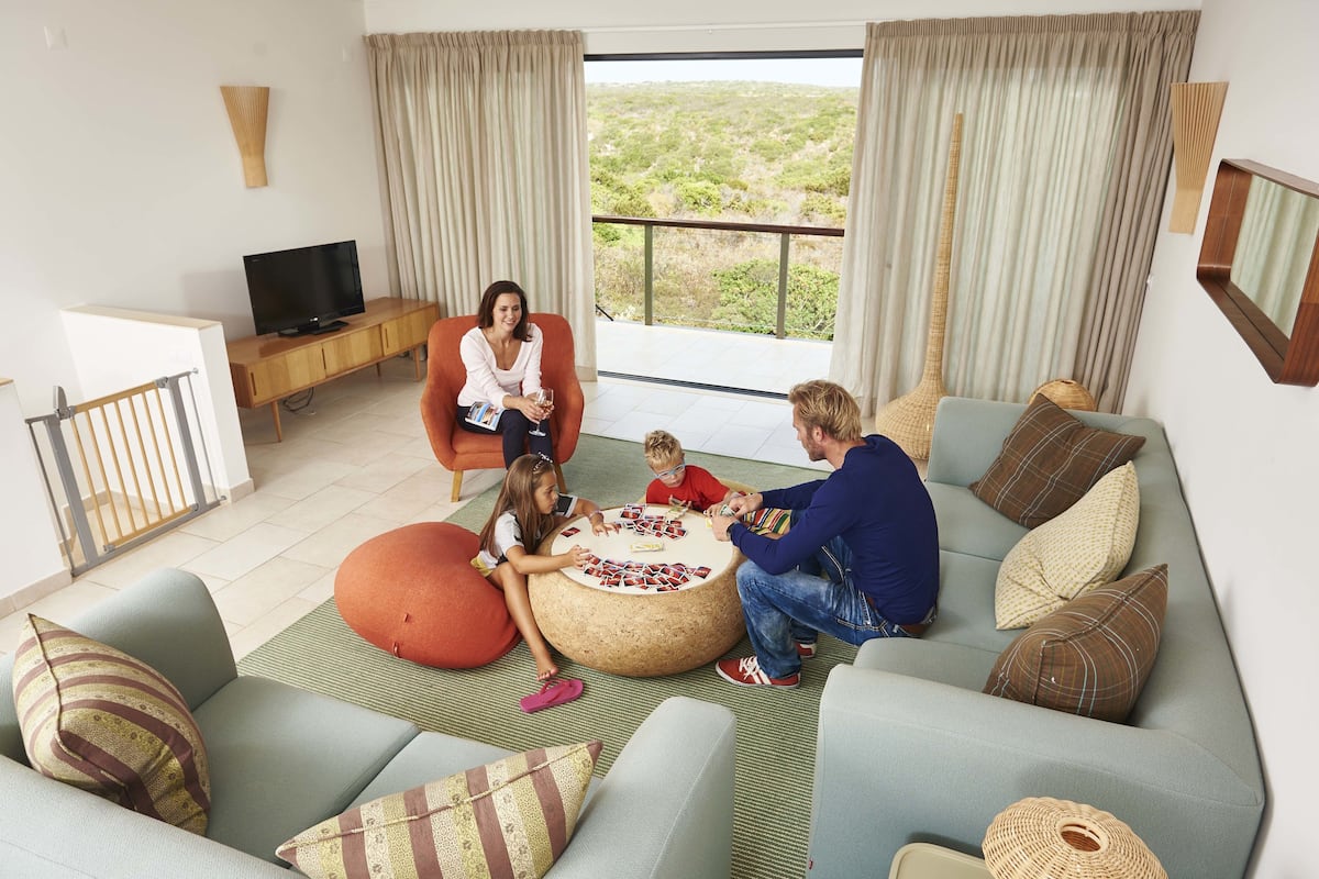 A living room with a sofa, ottoman, and a television.