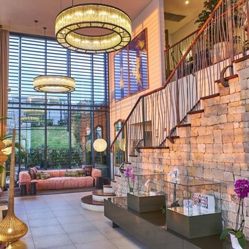 A spacious lobby with a stone wall, a staircase, and a large window offering a view of greenery.