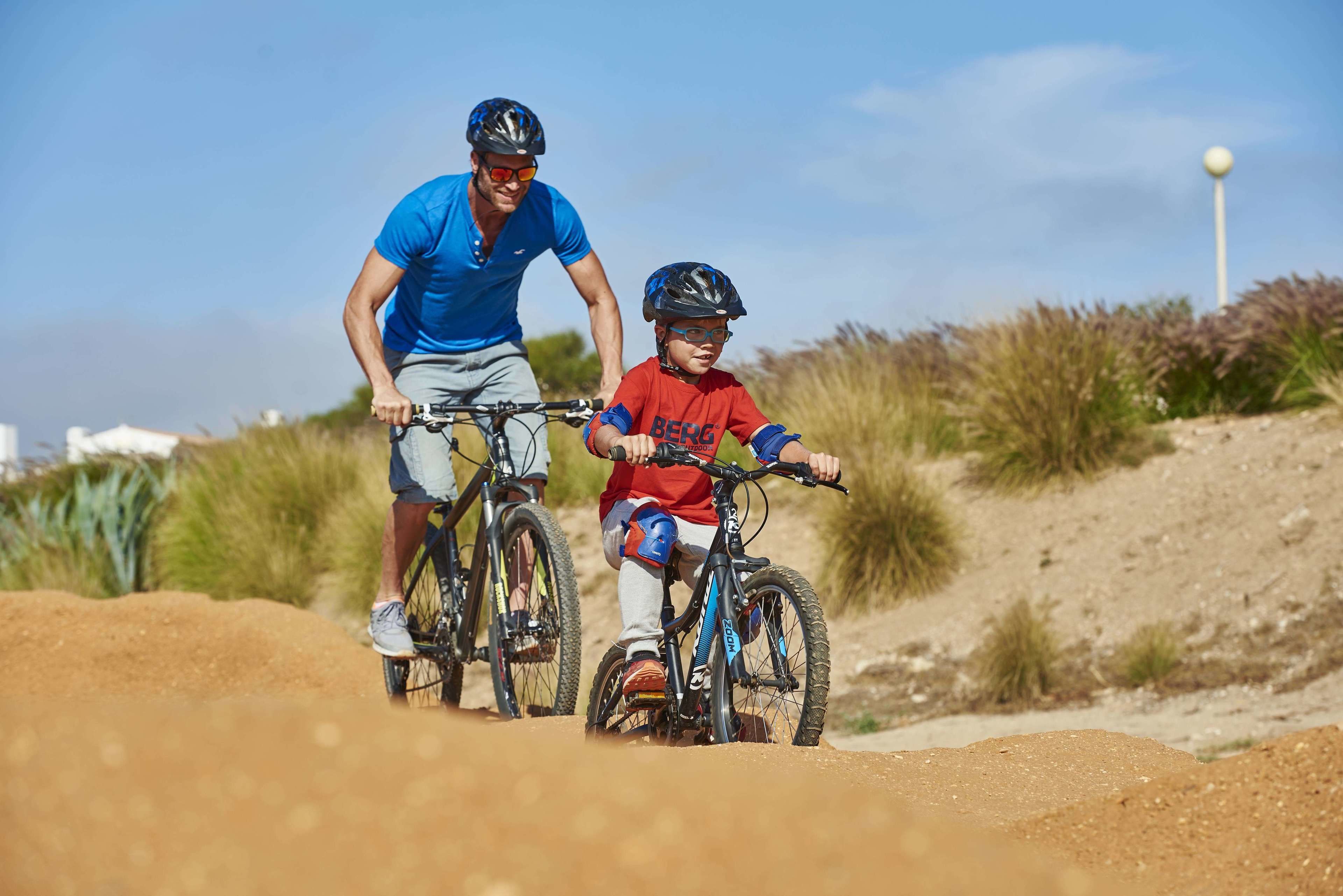 A man and a child on mountain bikes on a dirt trail.