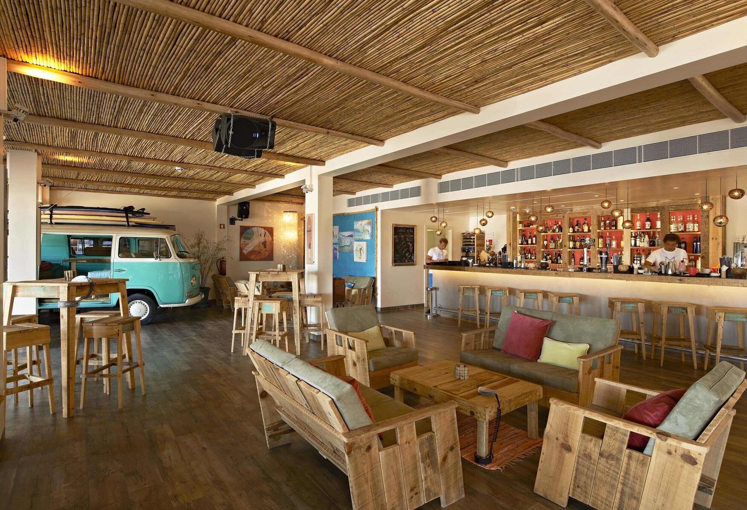 Un interior rústico con muebles de madera, un coche antiguo y una zona de bar.